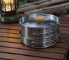 Soup Pot Pan Set of 2 stainless steel cooking pots with wooden lid on a wooden table next to a lantern.