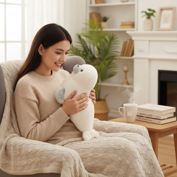 A person hugging a Plush Seal Soft Toy while sitting on a cozy couch with a warm drink.