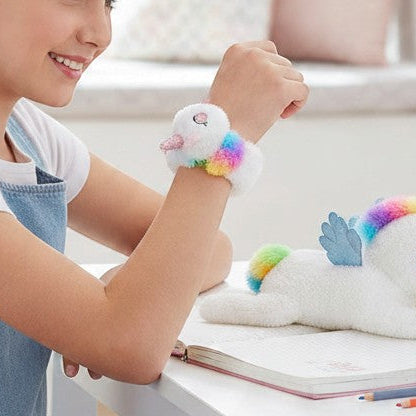 Girl wearing a colorful Slap Unicorn Bracelet while sitting at a desk with a notebook and a plush unicorn.