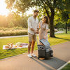 Couple using a Rolling Trolley Bag with Front Pocket & Mesh Panels in a park during sunset.