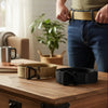 Two Tactical-Style Quick Release Belts, one in beige and one in black, displayed on a table.