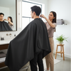 Water-Resistant Haircut Apron & Barber Cutting Cape used during a haircut in a modern salon setting.