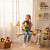 Girl hugging a colorful Plush Parrot Toy while sitting on a swing in a cozy room.