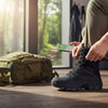 Mens Tactical Side Zip Work Boots worn by a person, with a backpack and smartphone nearby in an outdoor setting.