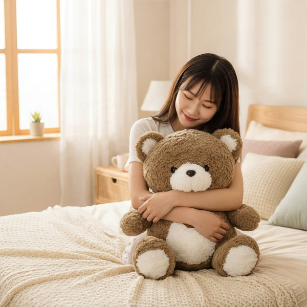 Soft Plush Teddy Bear Toy with Neck Pendant being hugged by a girl on a cozy bed in a bright room.