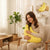 A woman relaxing on a chair, hugging a 50cm Bean Plush Banana for comfort and decorative appeal.