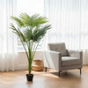 Artificial Palm Tree in Nursery Pot beside a grey chair in a bright room with natural light.