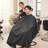 Water-Resistant Haircut Apron & Barber Cutting Cape protecting clothing during a haircut in a salon.