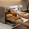 User operating the Silver 25L 3-in-1 Countertop Electric Oven & Air Fryer Unit with a tray of vegetables and chicken.