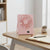 Portable Rechargeable Desktop USB Fan on a desk, providing personal airflow in a stylish pink design.